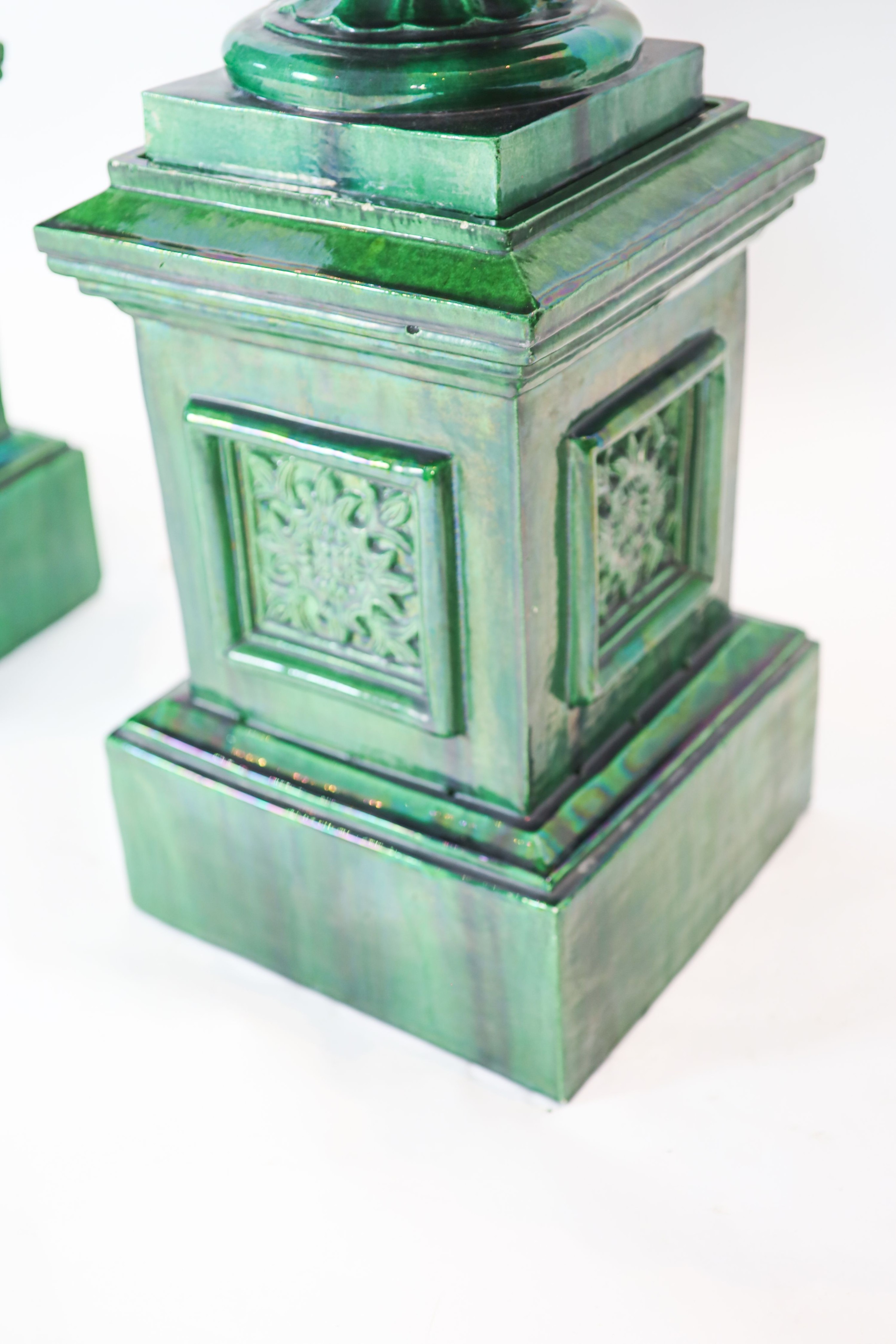 A pair of large dark green glazed terracotta fluted urns, raised on square plinths, diameter 50cm, height 101cm